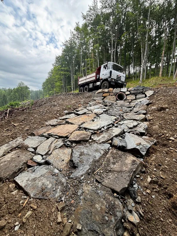 Tatra při navážení kamene k propustku v lesním terénu